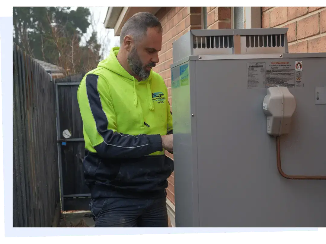 Plumber servicing gas hot water system at residential property