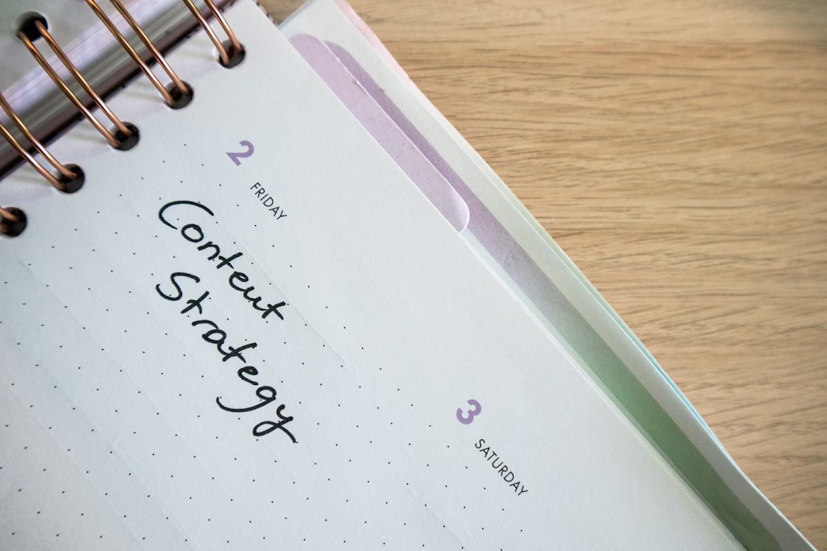 Source: Walls.io, Unsplash.com, Free-to-use licence. Open planner with 'Content Strategy' written on Friday, February 2. 