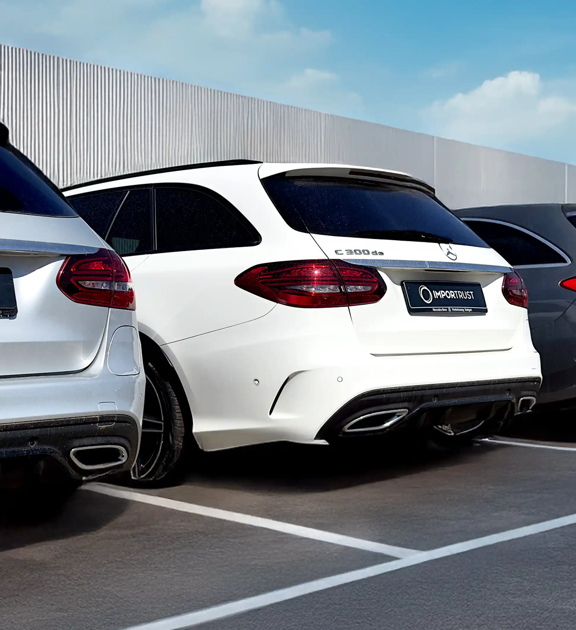 Fotografía de tres coches aparcados en paralelo. El del centro es un Mercedes-Benz C 300de blanco, con matrícula de Importrust