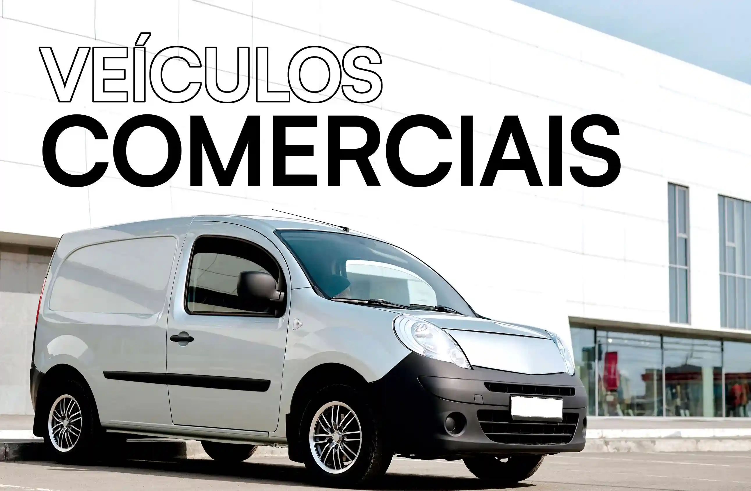 Carrinha comercial cinzenta estacionada em frente a um edifício moderno com janelas de vidro, acompanhada do texto 'Veículos Comerciais' em destaque